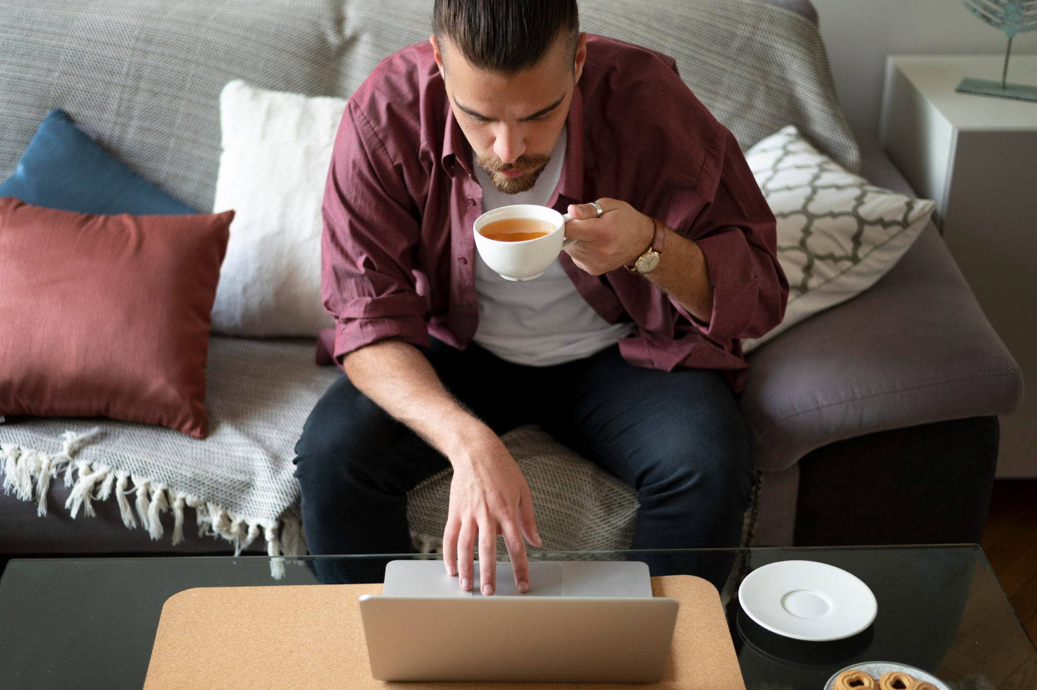 man drinking tea and working on laptop
