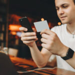 man in headphones holding card and phone